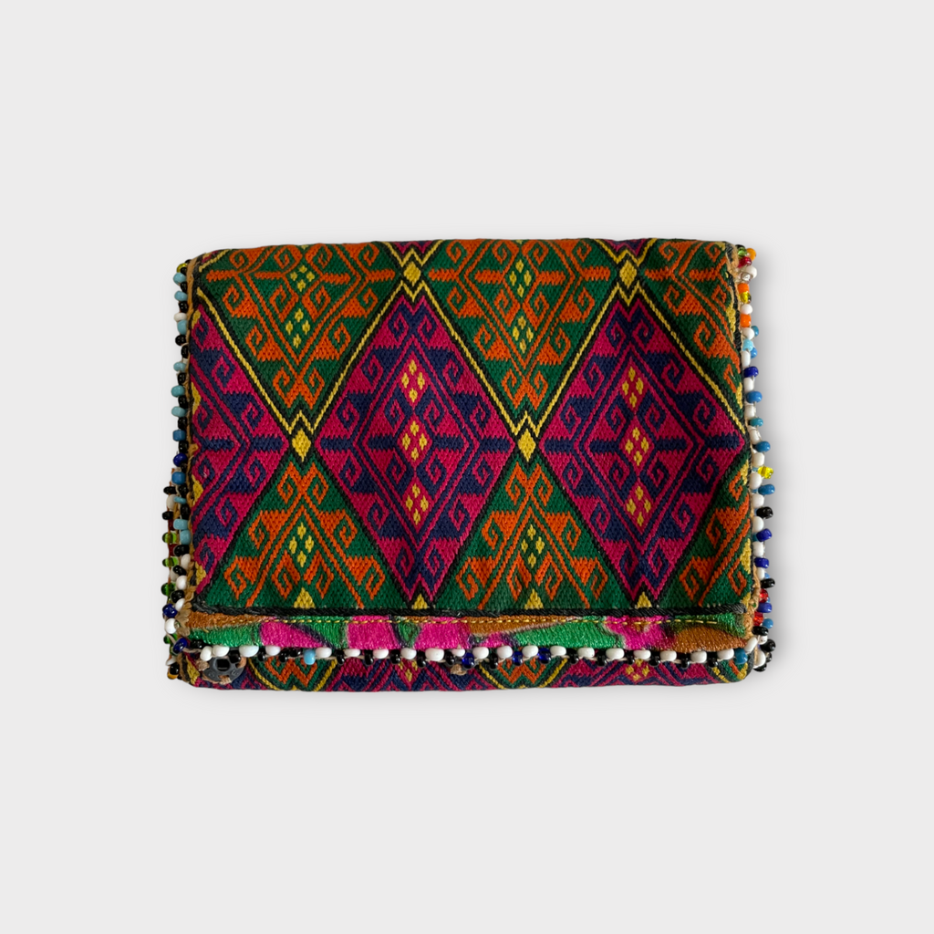 A vintage silk wallet with geometric diamond-shaped embroidery in multiple colors, featuring a snap closure and a floral pattern lining.